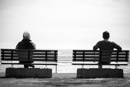 灰度照片2人坐在海邊的長椅上