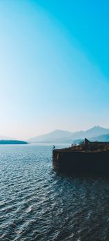 Tranquil ocean scene with mountains in the background and a serene blue sky.