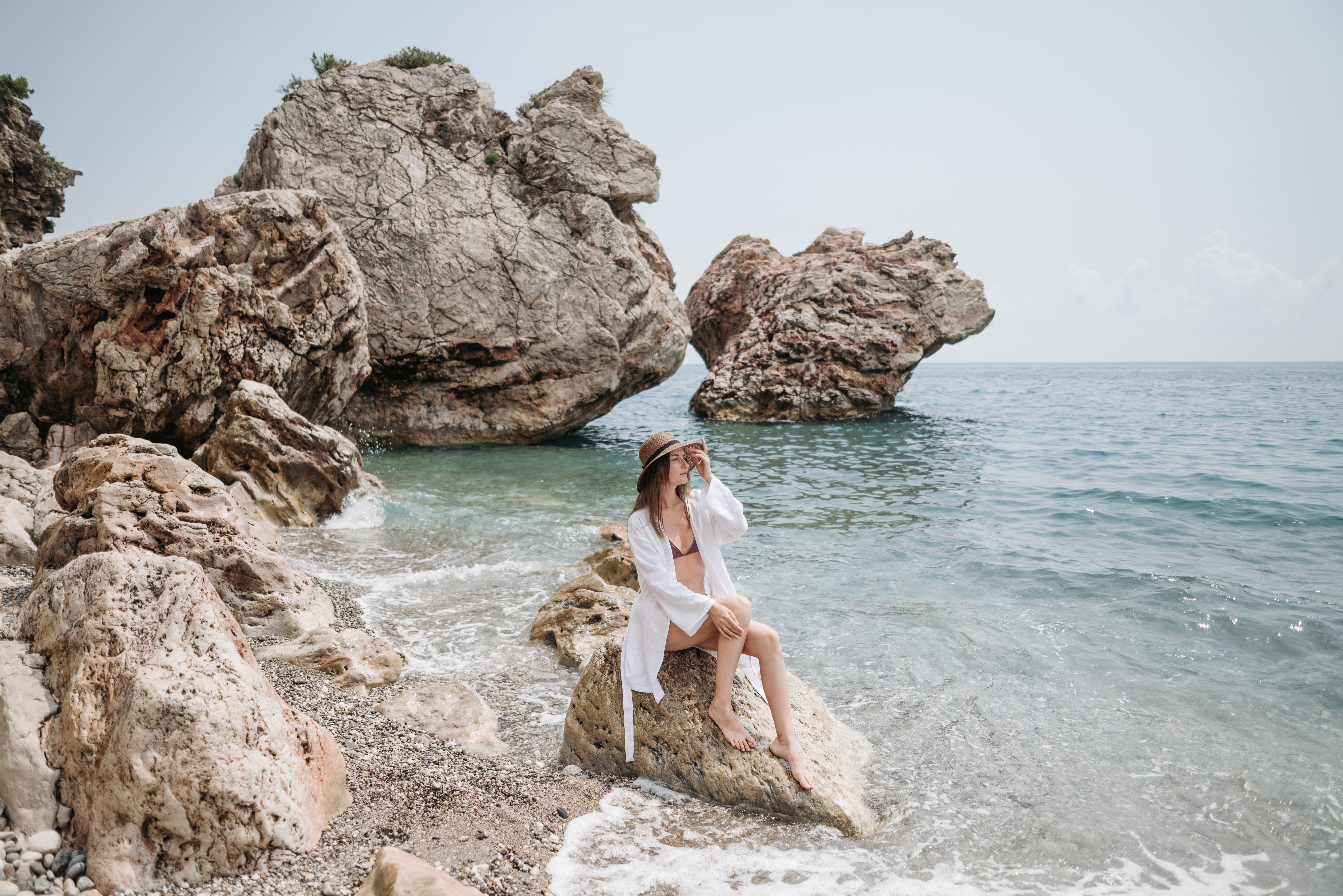 A person wearing a wide-brimmed hat and sunglasses, enjoying the sunny Croatian coastline.
