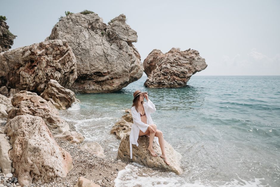 A person wearing a wide-brimmed hat and sunglasses, enjoying the sunny Croatian coastline.