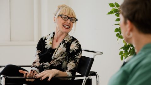 Blonde woman with glasses actively talking during an indoor counseling session.