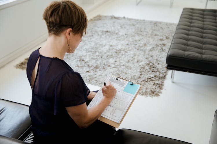 A Woman Holding A Clipboard And Writing