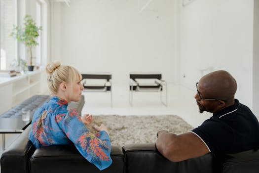 Two individuals discussing in a bright, modern indoor setting. Mental health mentorship emphasis.