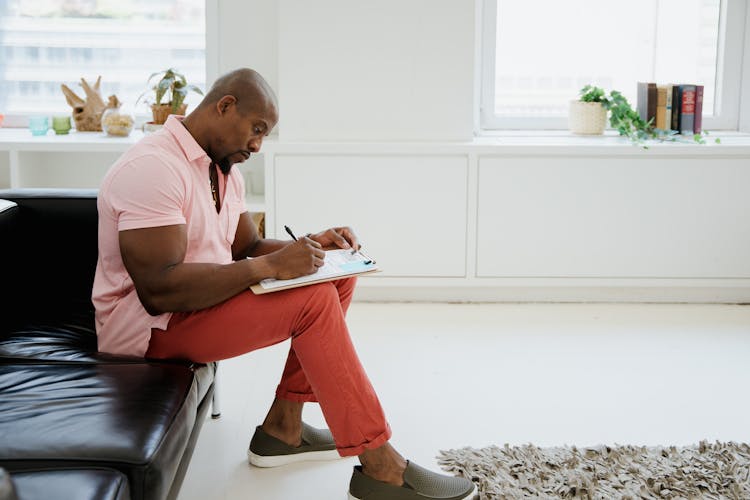 A Man In A Pink Polo Shirt Filling Out A Form