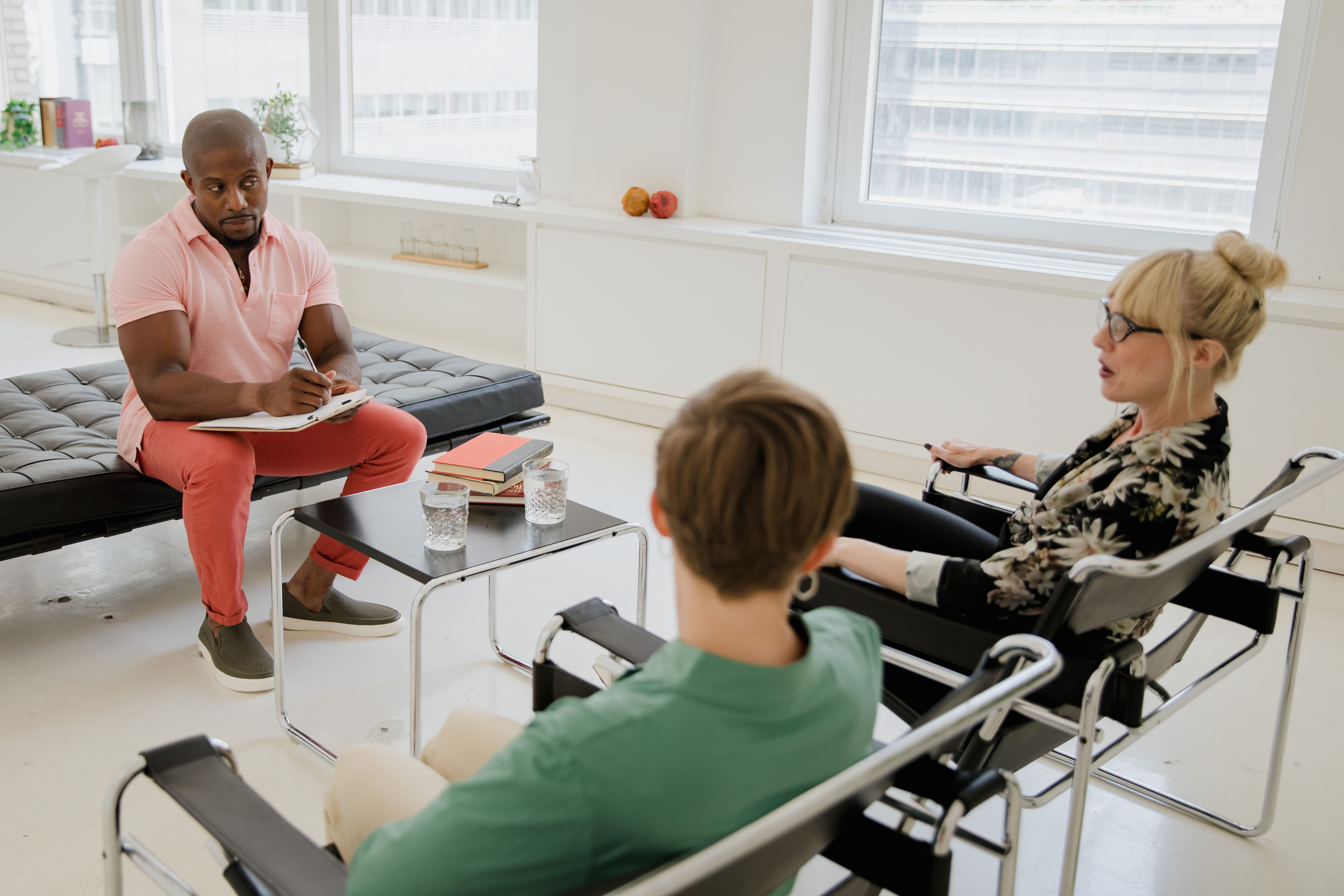 A therapist leads a counseling session with two adults discussing mental health.