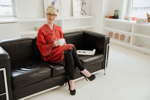 Woman in Red Coat Sitting on Sofa With Crossed Legs 