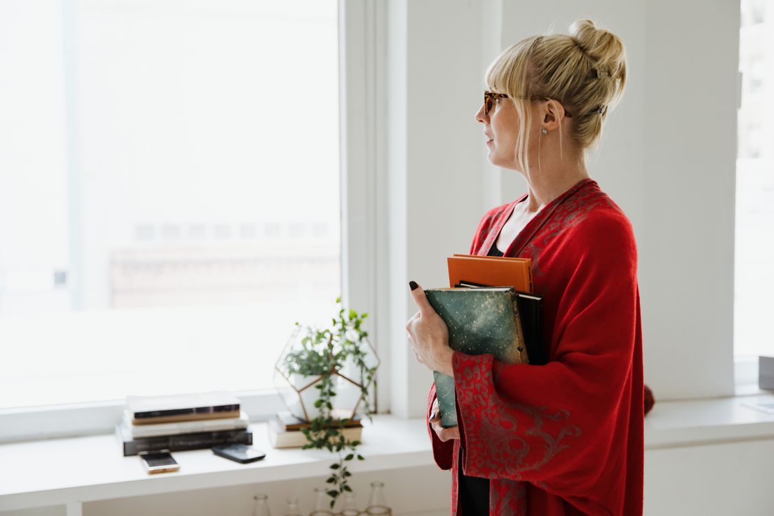 A Woman in a Red Robe Holding Books · Free Stock Photo