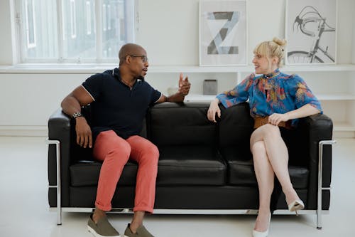 Free A Man and Woman Sitting on the Couch while Having Conversation Stock Photo