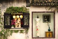 Beautiful display of traditional Chinese dresses in a quaint vintage shop window.