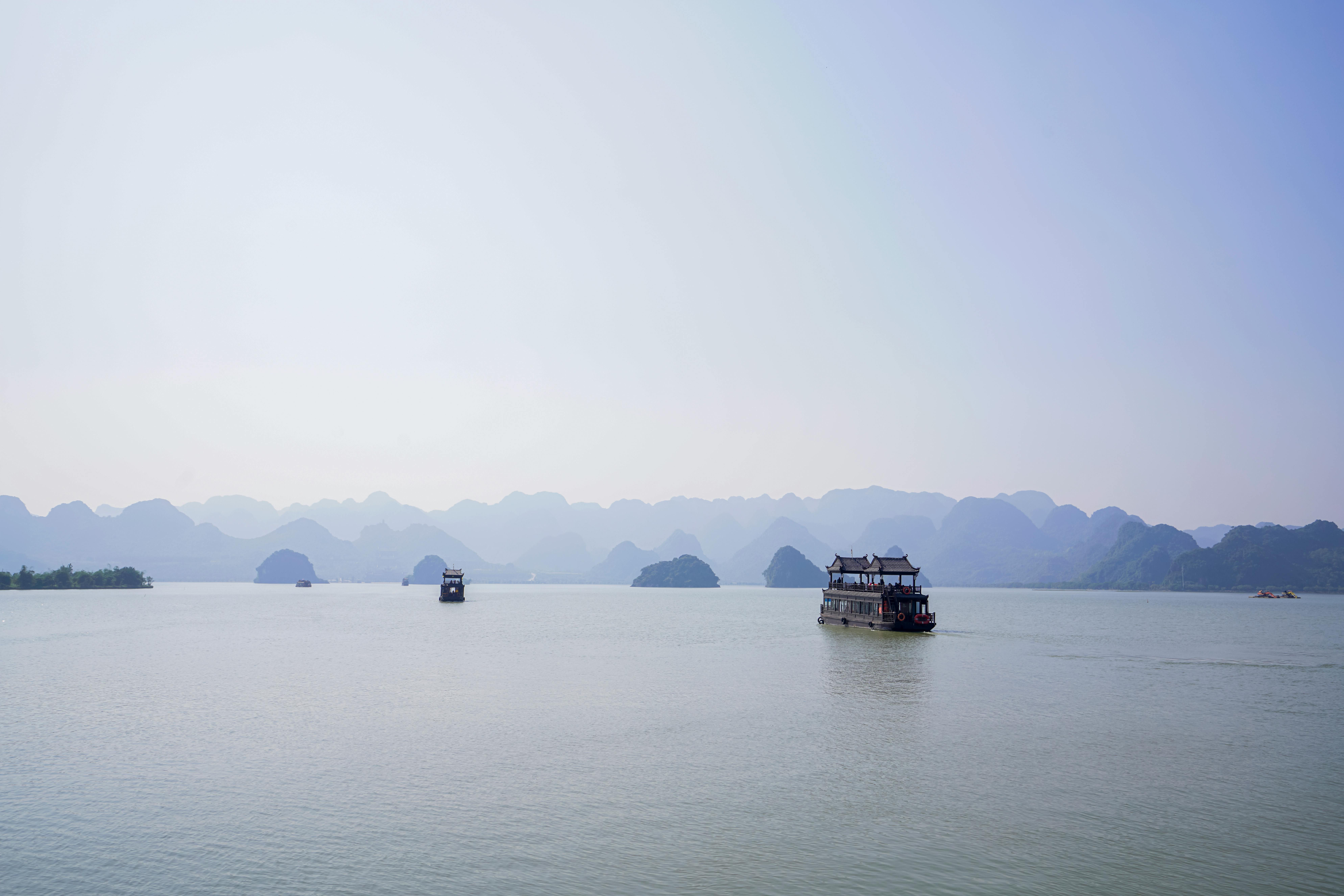 Local boat with roof sailing on rippling sea against mountain range and blue sky in coastal area on summer day
