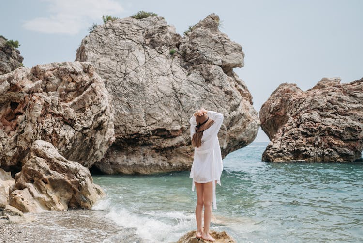 Woman Standing On A Rock In The Beach