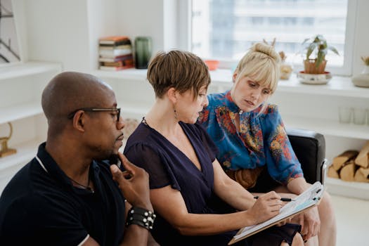 Three diverse adults engaged in a thoughtful discussion in a modern office setting.