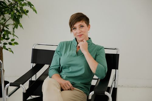 Free Portrait of a woman with short hair sitting confidently in a modern black chair indoors. Stock Photo