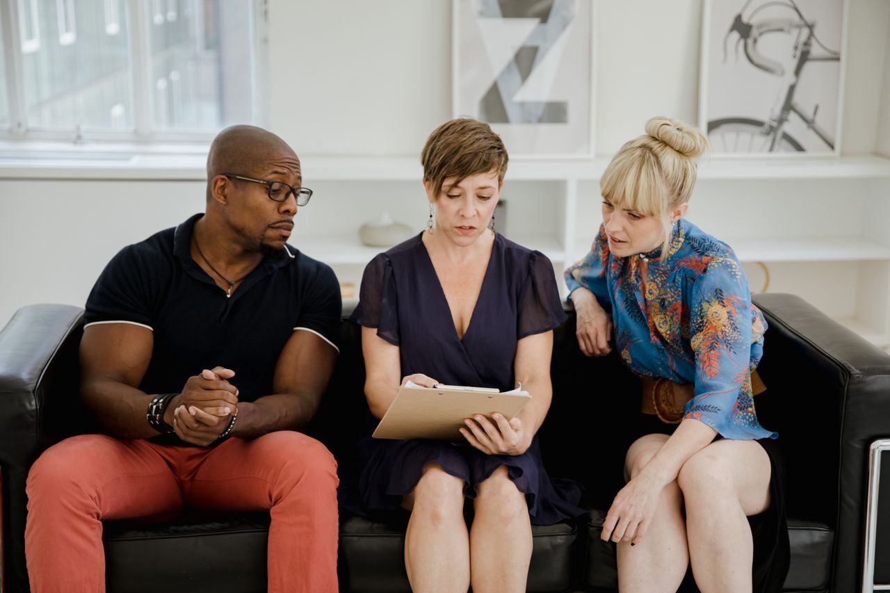 three adults discussing content on a clipboard in a contemporary offic
