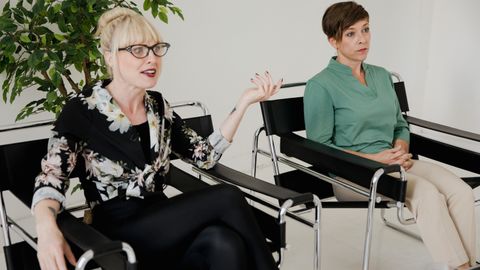 Two women having a conversation in a modern therapy office setting.