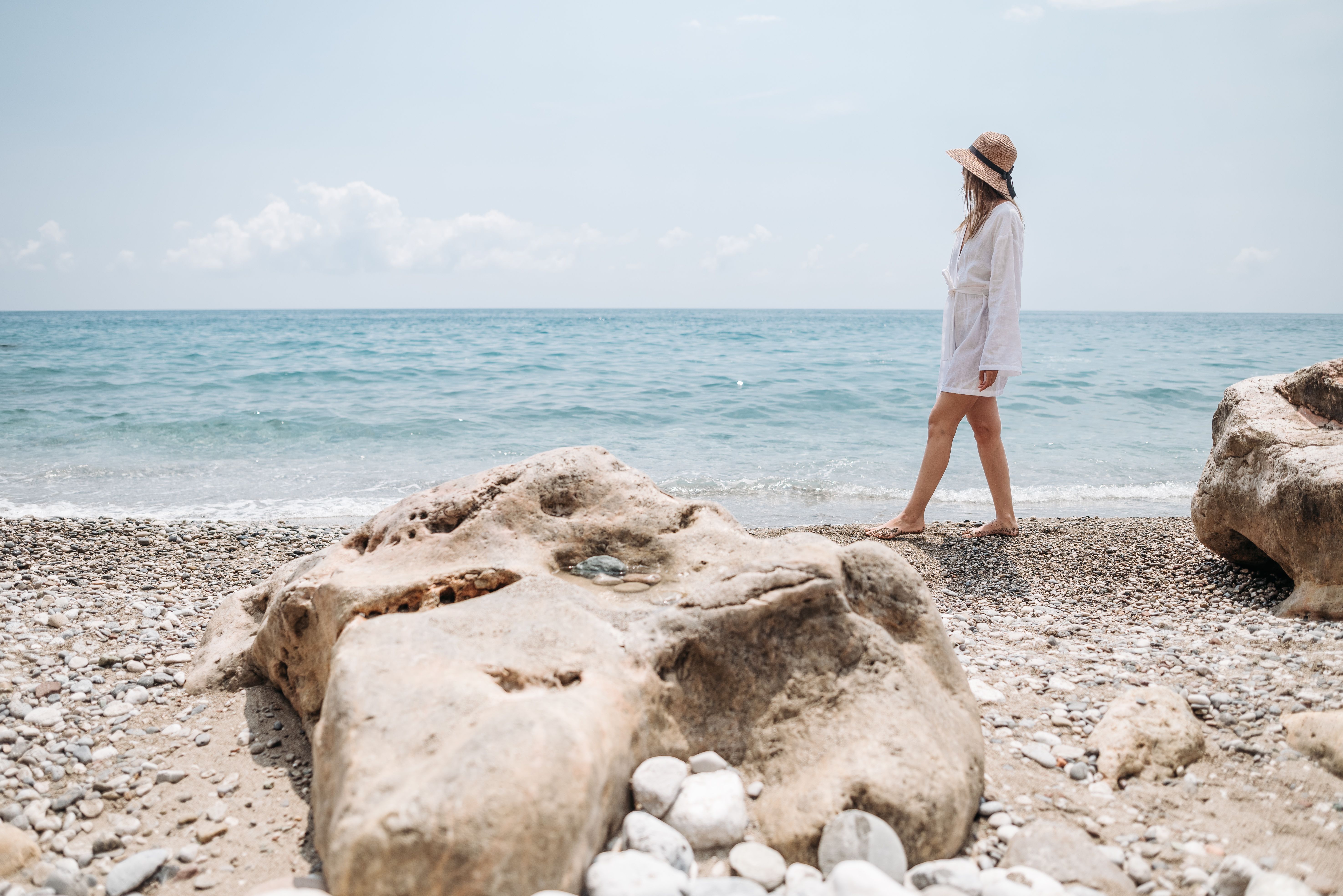 Woman in a White Shirt and Hat Walking on a Beach · Free Stock Photo