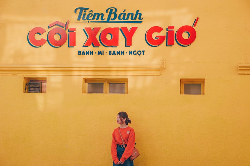 Asian woman standing against colorful wall with Vietnamese text, vibrant urban scene.