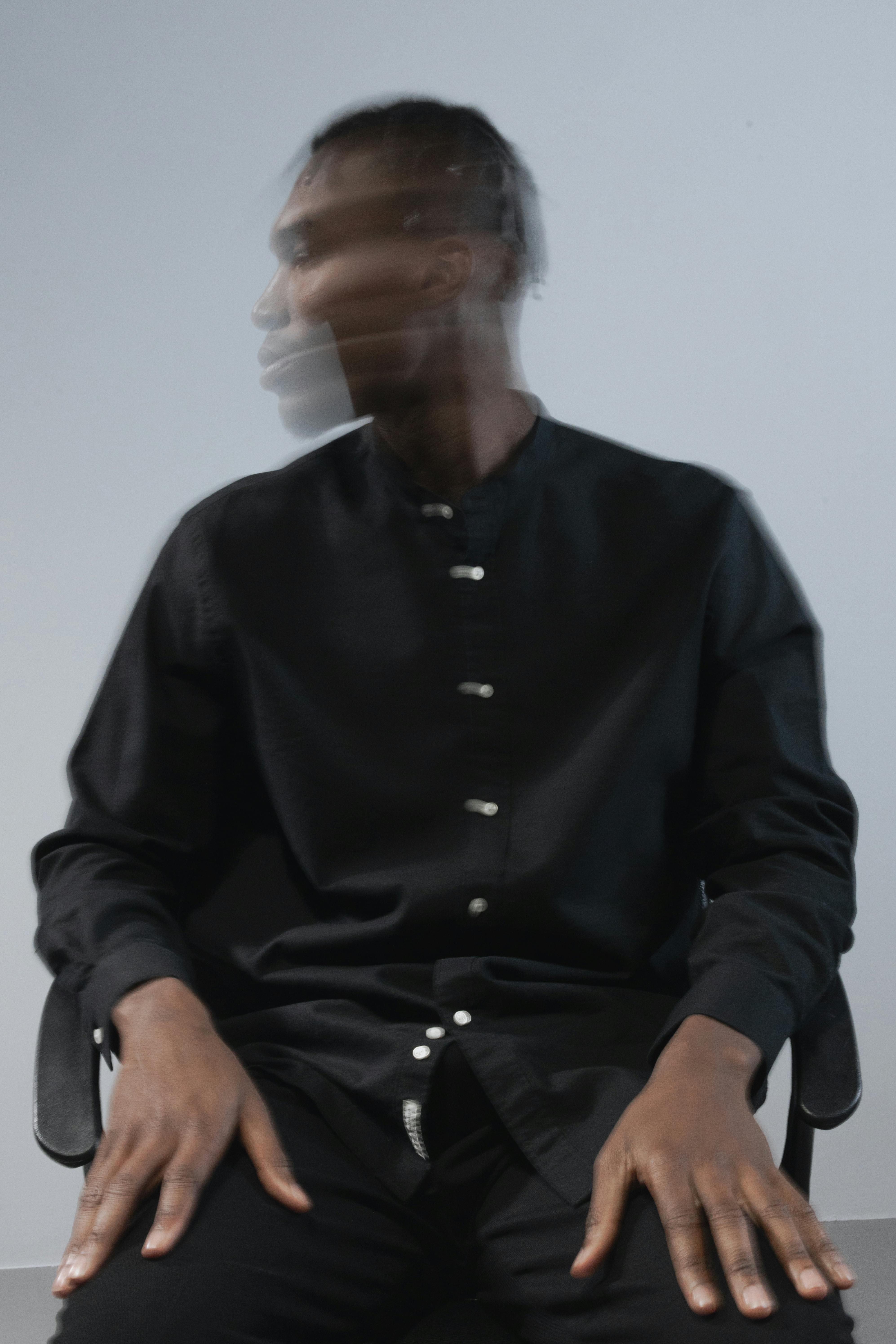 Blurred motion portrait of a man sitting indoors with a modern artistic style.