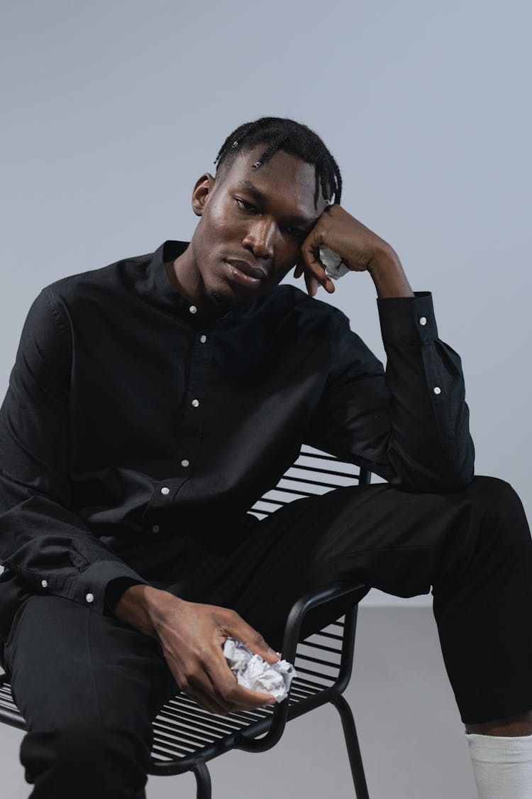 Young Man Sitting On A Chair And Holding Scrunched Paper