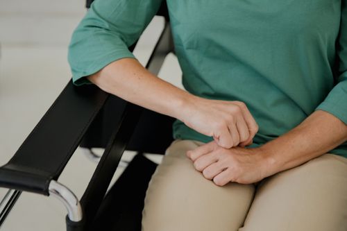 Free Detailed image of hands resting on a chair armrest, wearing a green shirt. Stock Photo