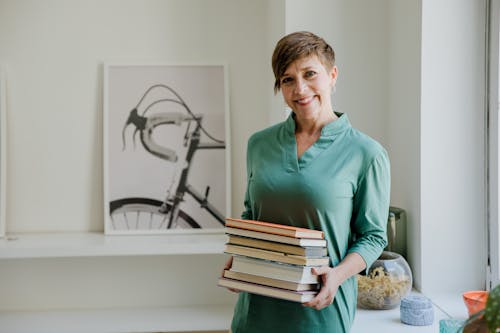 Woman in Green Long Sleeve Shirt Holding Books
