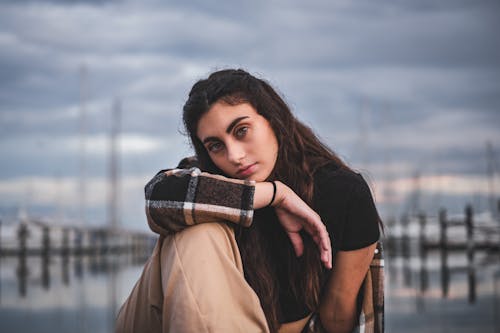 Woman Wearing Plaid Jacket Sitting on a Deck