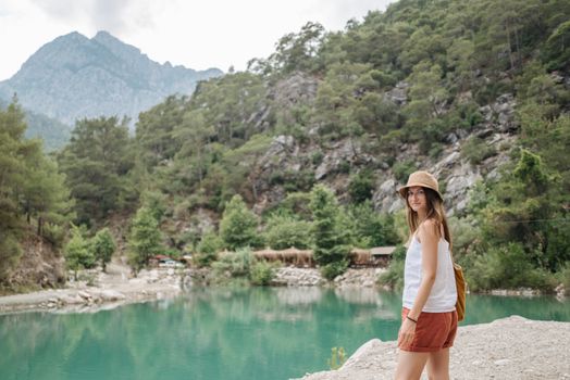 A woman explores a mountain trail by a serene stream in summer.