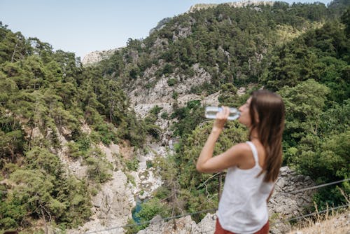 Free Woman Drinking Water on Mountain Top Stock Photo