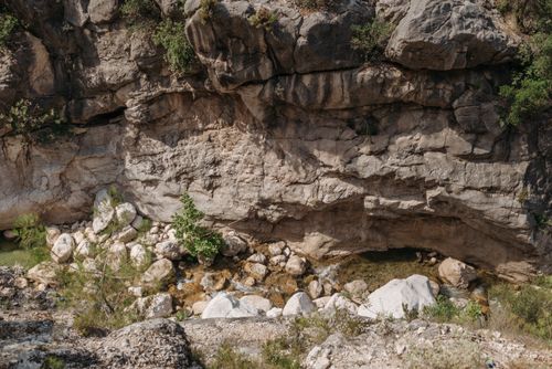 Free A scenic view of a rocky cliffside with a small stream and natural vegetation. Stock Photo