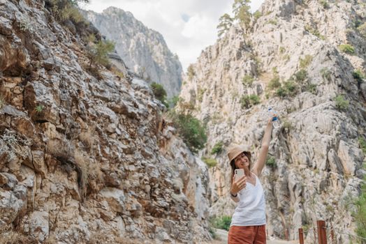 A woman takes a selfie in a stunning rocky canyon, capturing the essence of adventure.