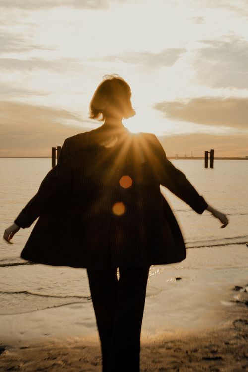 Free A woman enjoys a serene sunset on the beach in Saint Petersburg, Russia. Stock Photo