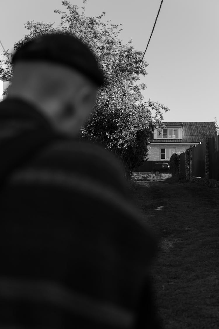 Black And White Photo Of Man Walking Towards Building 