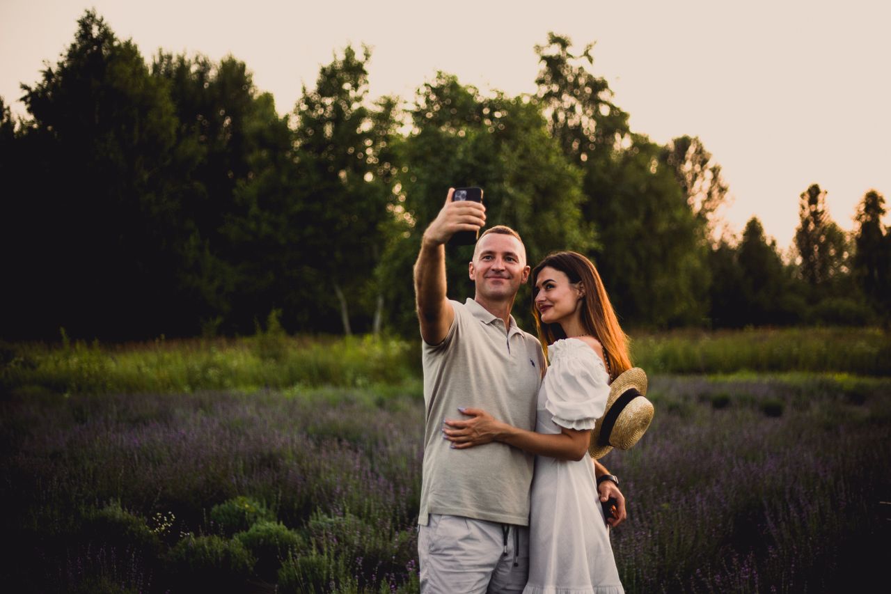 A couple takes a selfie in a lavender field at sunset