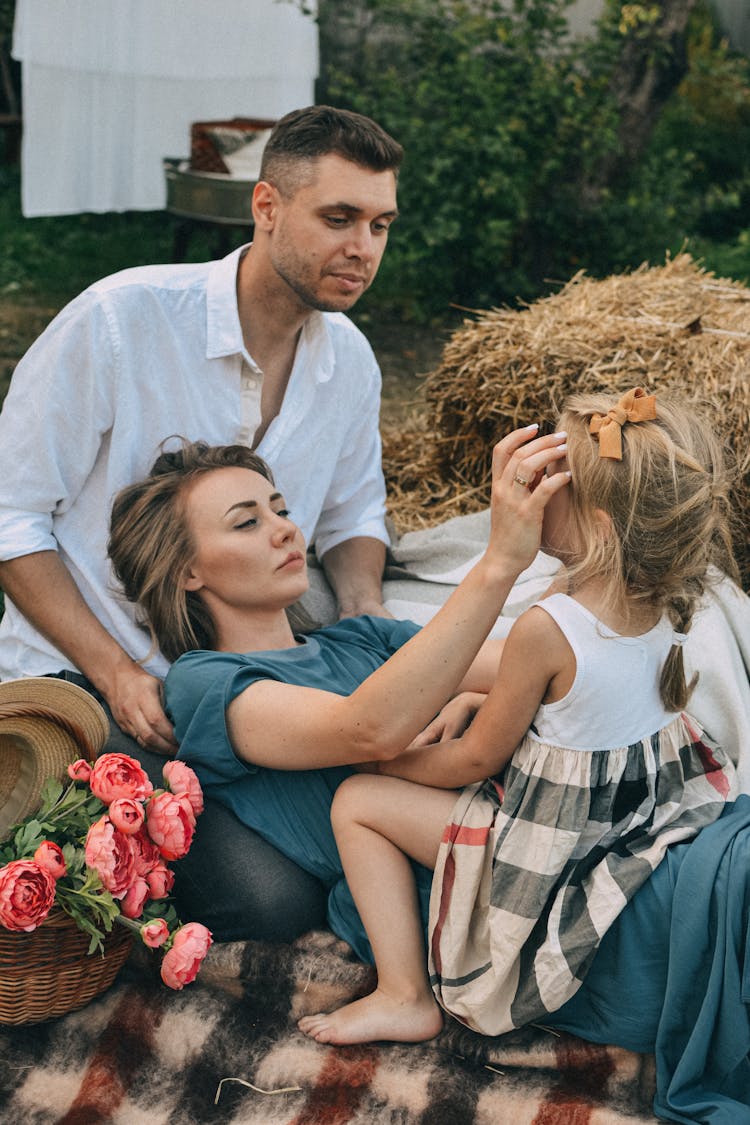 Family Photo Of Parents And Their Daughter On A Picnic 