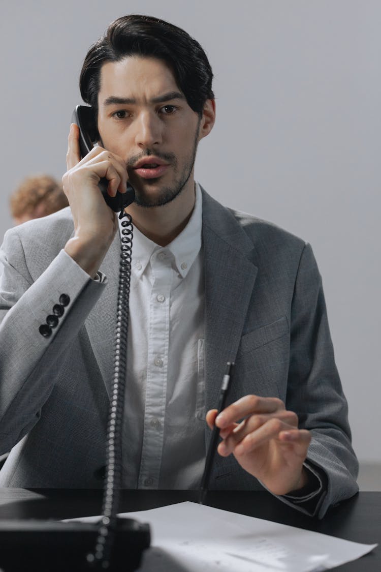 A Man In Gray Suit Talking On The Phone