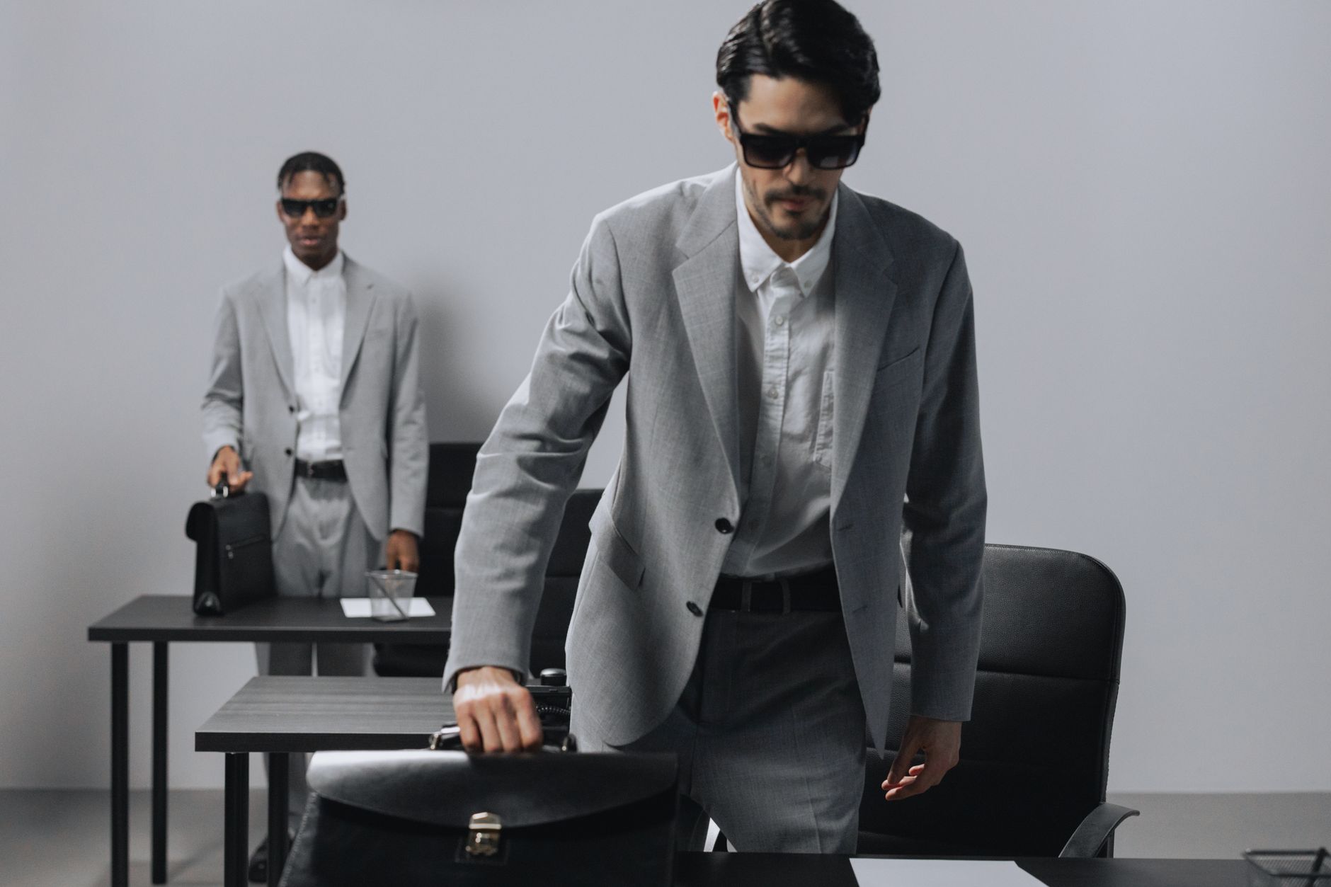 Two professional men in gray suits in an office, exuding a serious and modern business atmosphere.