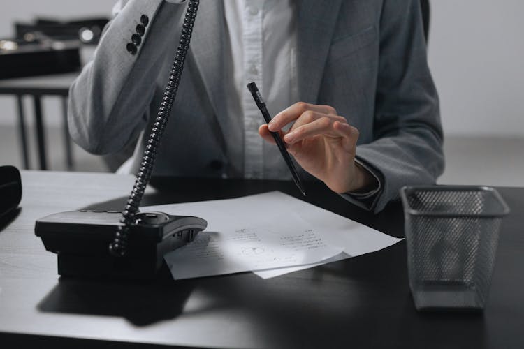 Person Talking On The Telephone While Holding A Pen 