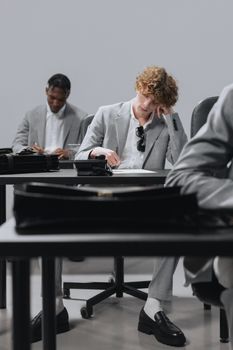 Two men in business attire concentrating on an exam in an office setting.