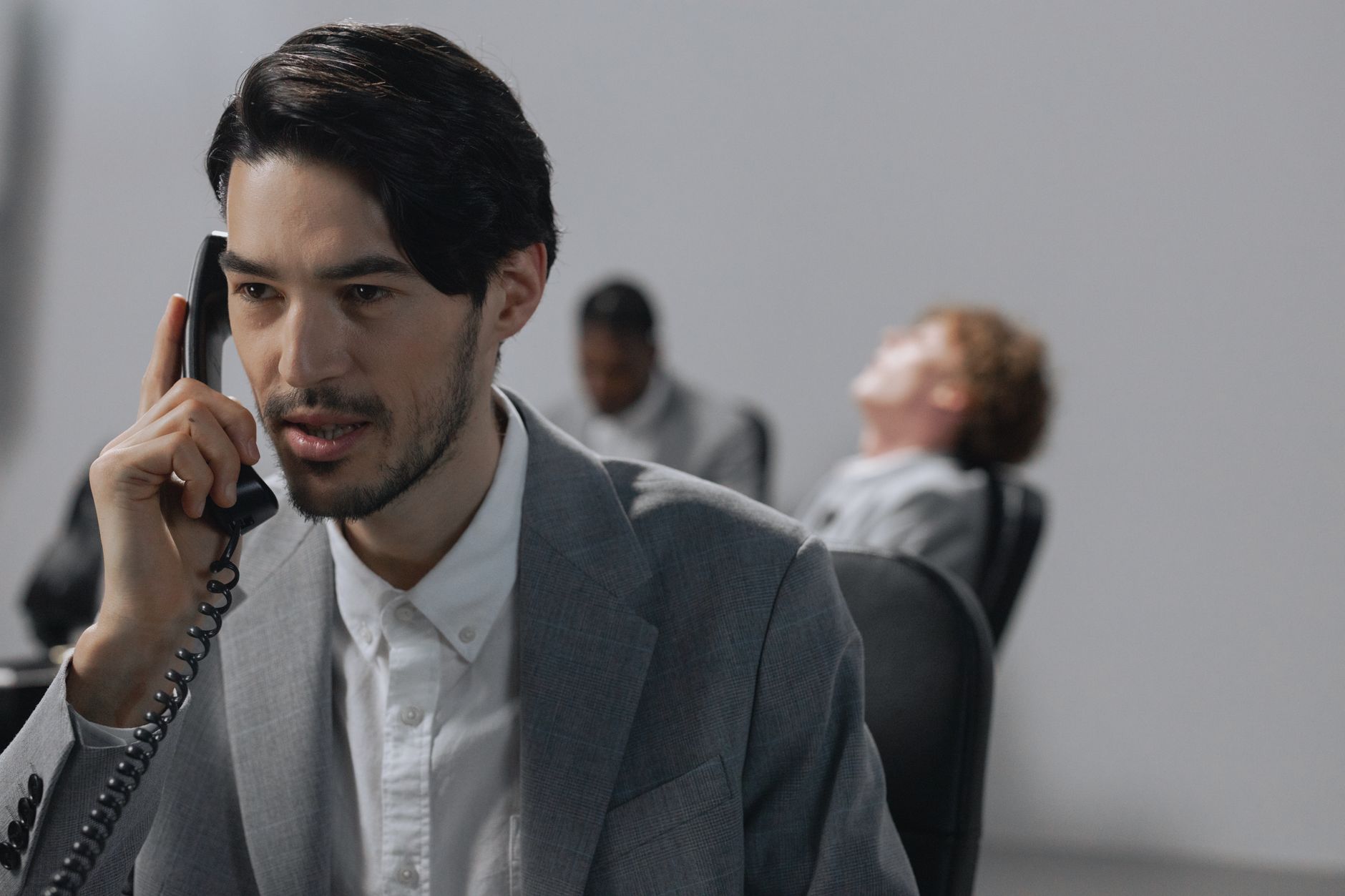 Young businessman in gray suit on phone, emphasizing office communication.