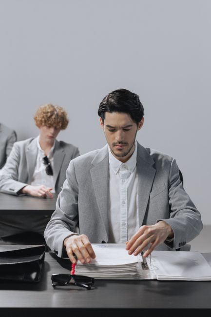 Men in business attire focusing on documents in a modern office setting. Men in business attire focusing on documents in a modern office setting.