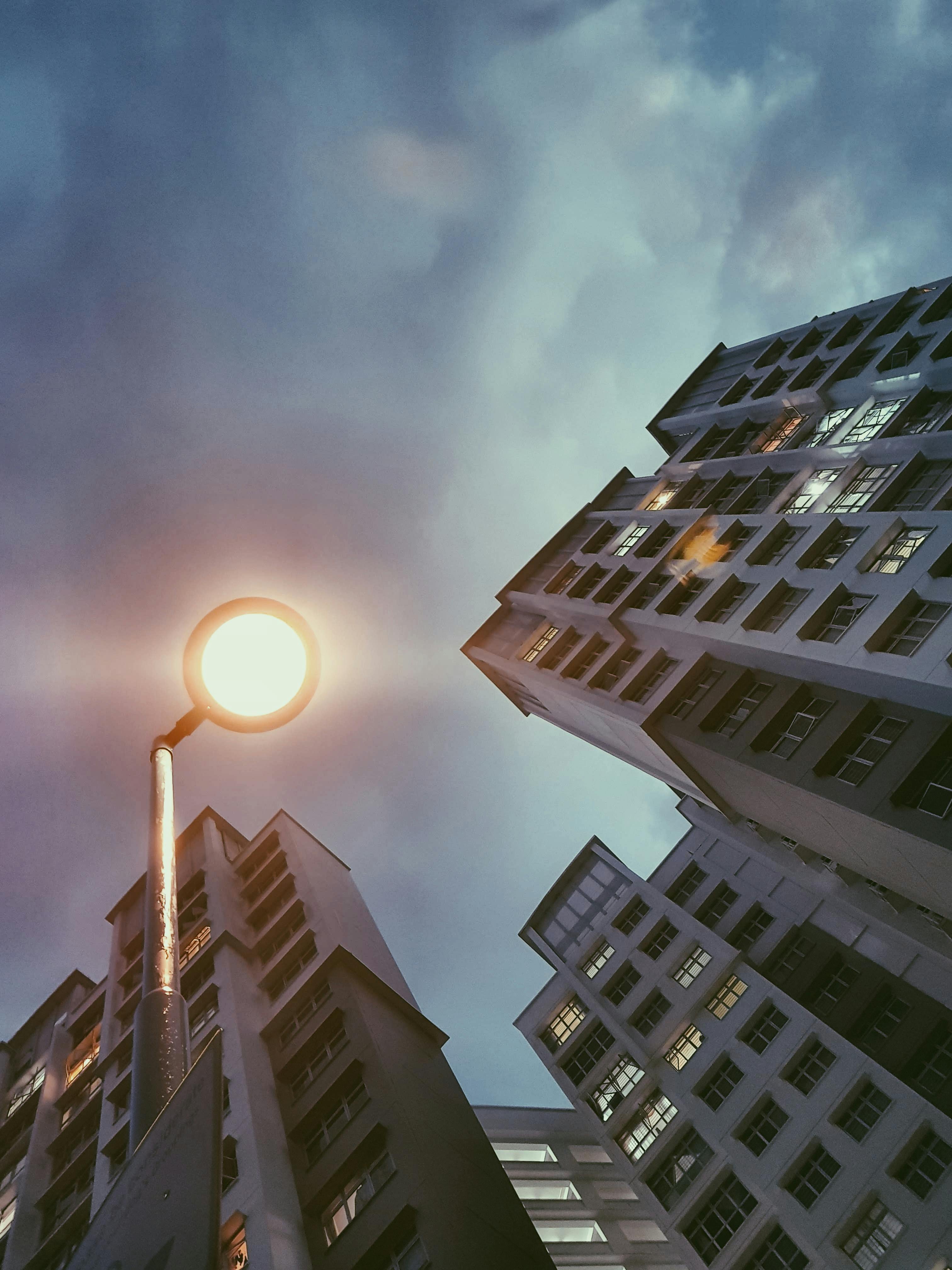 Low Angle Photography Of Lamp Post Beside Building Under Cloudy