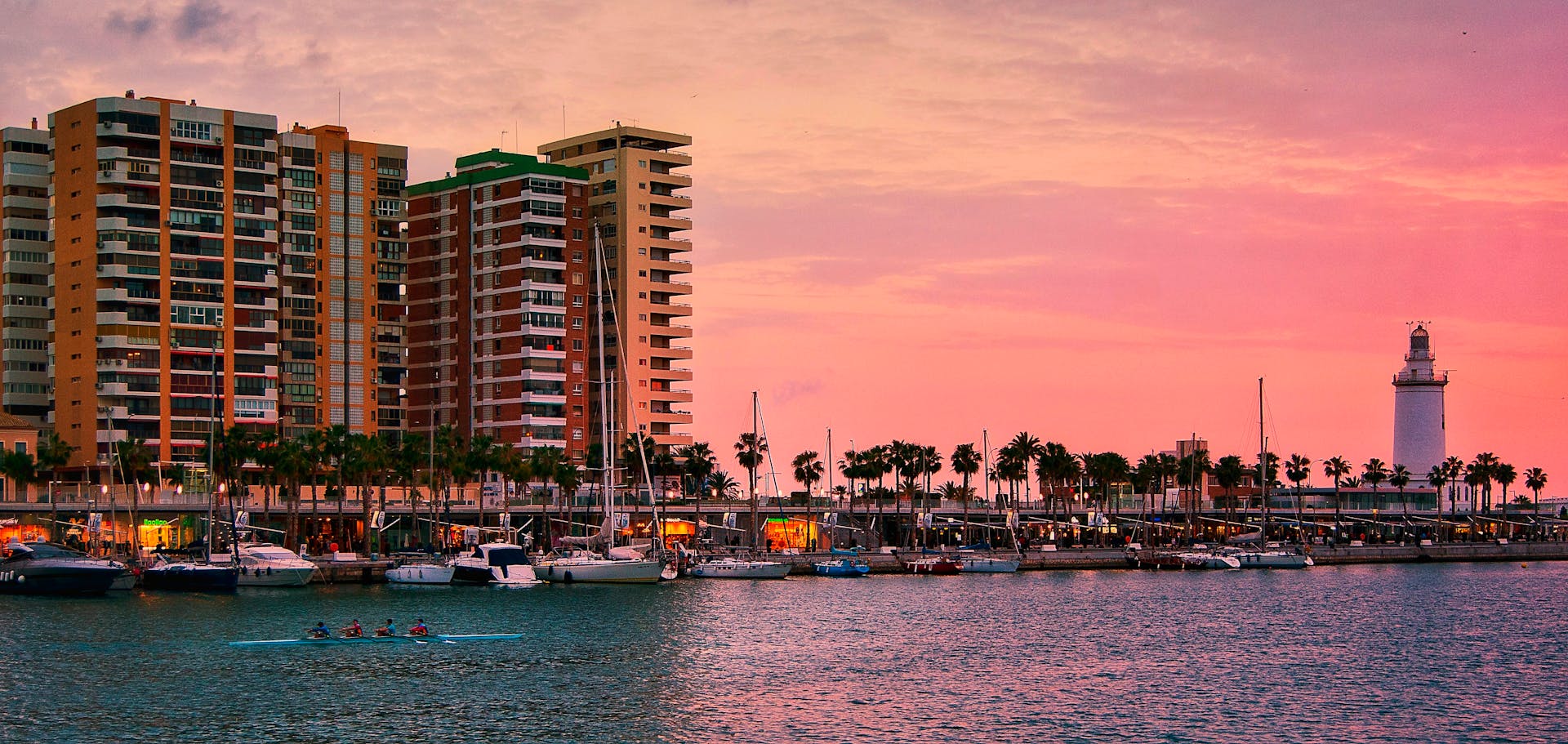 Vibrant harbor scene with yachts, buildings, and a stunning pink sunset sky.