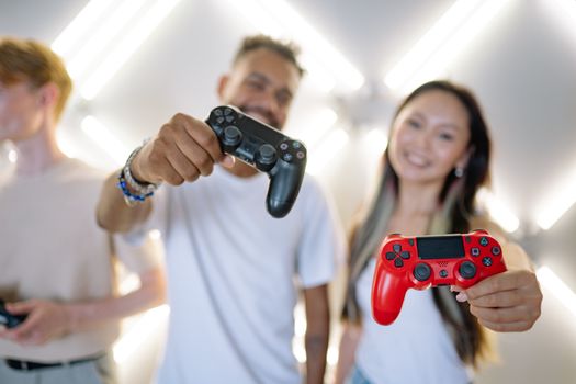 A diverse group of friends enjoying gaming indoors, holding controllers with a bright background.