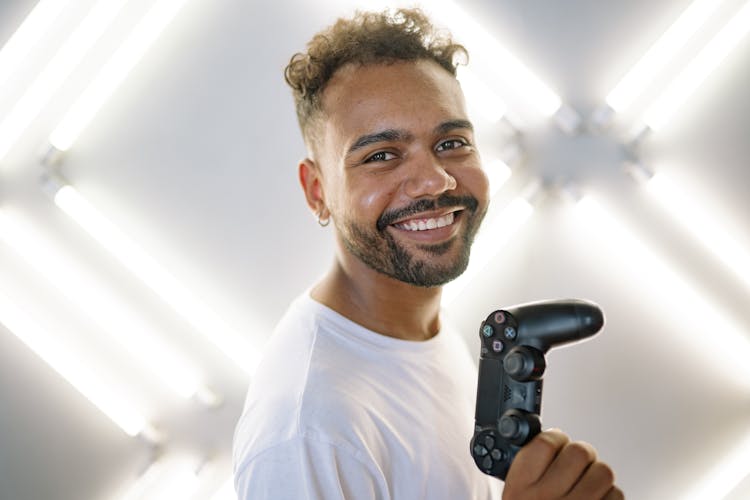 Man In A White Crew Neck Shirt Holding A Black Game Controller