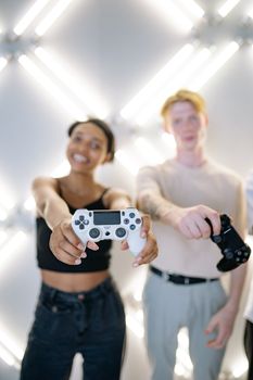 Two young adults having fun gaming indoors, holding controllers and smiling.