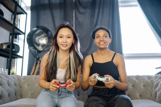 Two young women enjoying video gaming indoors, showcasing friendship and leisure time.