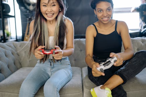 Two Women Playing Video Games while Sitting on the Sofa