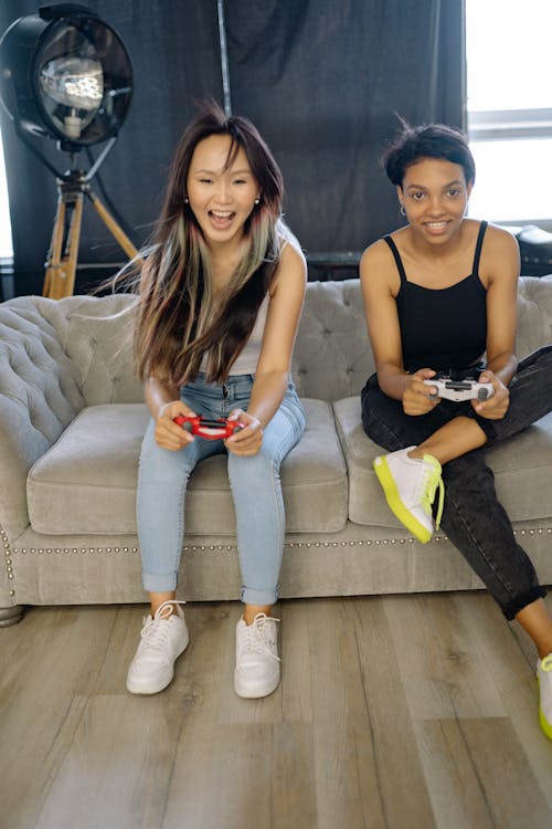 A Pair of Women Sitting on Couch Playing Computer Game