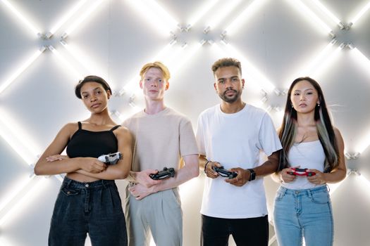 A diverse group of friends playing video games together indoors under bright lights.