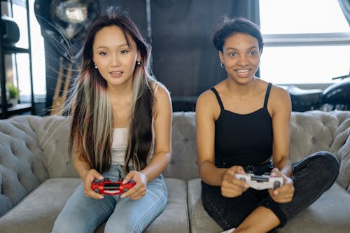 Two Women Playing Video Games while Sitting on the Sofa